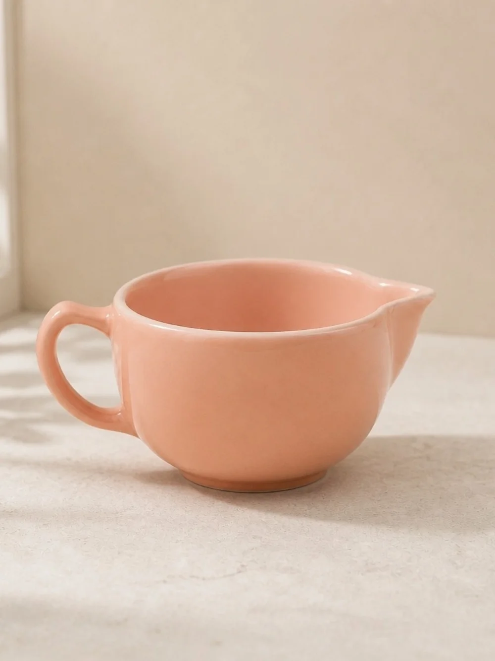 Vintage pink glass creamer by Hazel-Atlas with a C-shaped handle and spout